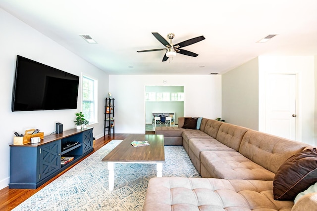 living room with visible vents, baseboards, light wood-style flooring, and a ceiling fan