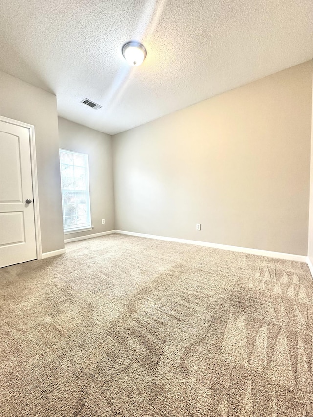 carpeted empty room featuring a textured ceiling, visible vents, and baseboards