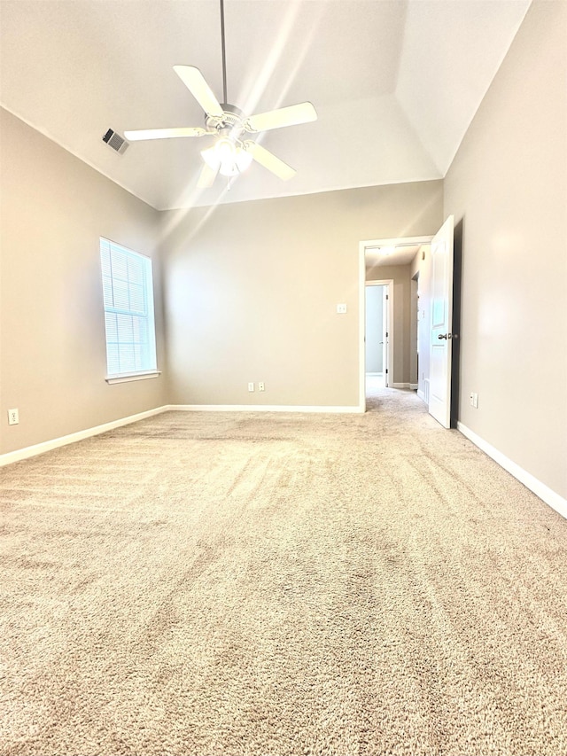 empty room with lofted ceiling, light colored carpet, visible vents, ceiling fan, and baseboards