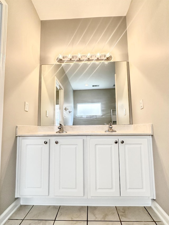 bathroom with double vanity, visible vents, baseboards, tile patterned floors, and a sink