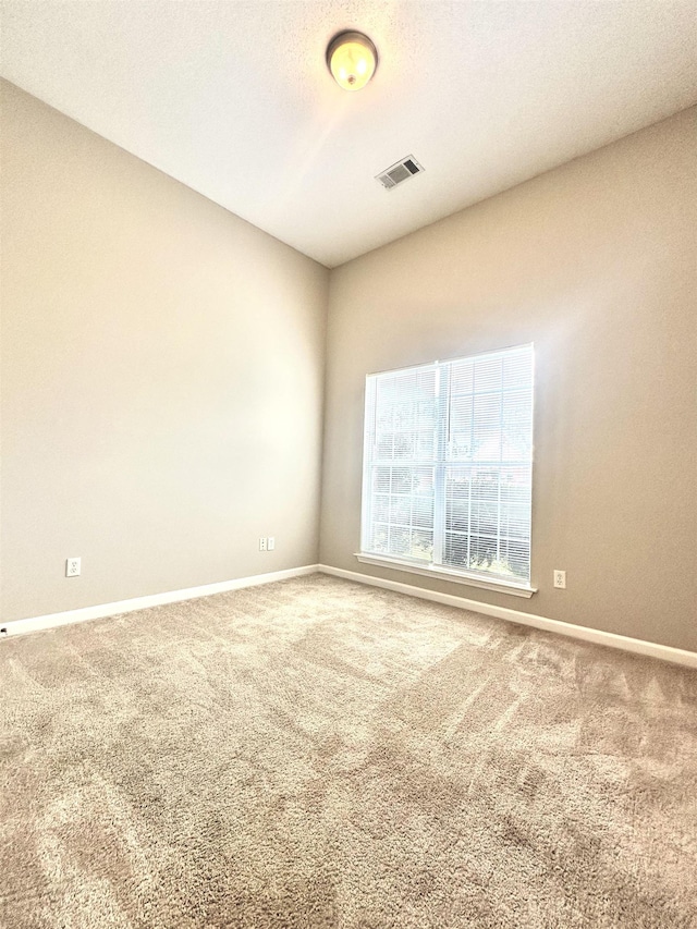 carpeted empty room featuring baseboards and visible vents