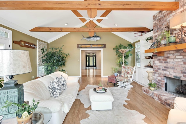 living room featuring lofted ceiling with beams, a fireplace, ornamental molding, and wood finished floors