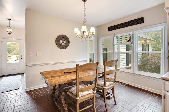 dining area featuring brick floor, baseboards, and an inviting chandelier