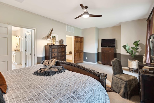 bedroom featuring light carpet, a ceiling fan, visible vents, ensuite bath, and crown molding