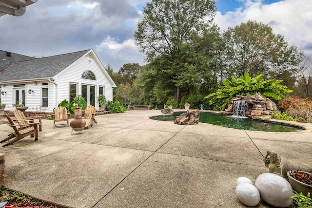 view of patio / terrace featuring french doors, an outdoor pool, and a fire pit