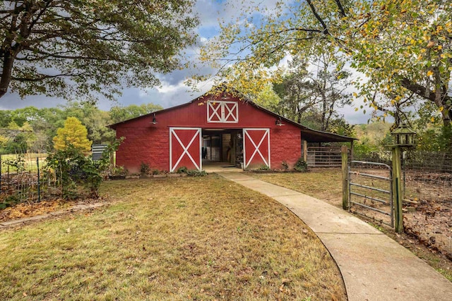 view of barn with a lawn and fence