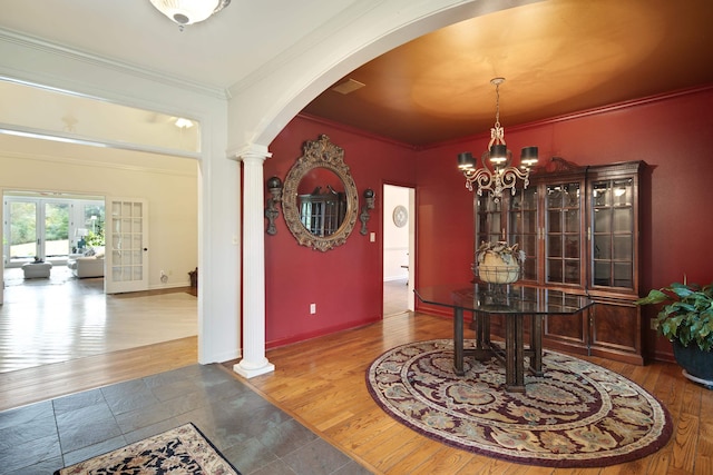 dining area with arched walkways, decorative columns, an inviting chandelier, ornamental molding, and wood finished floors