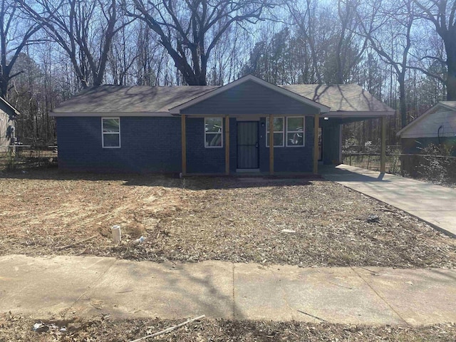 ranch-style house with concrete driveway, brick siding, and fence