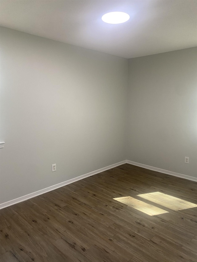 empty room with dark wood-type flooring and baseboards