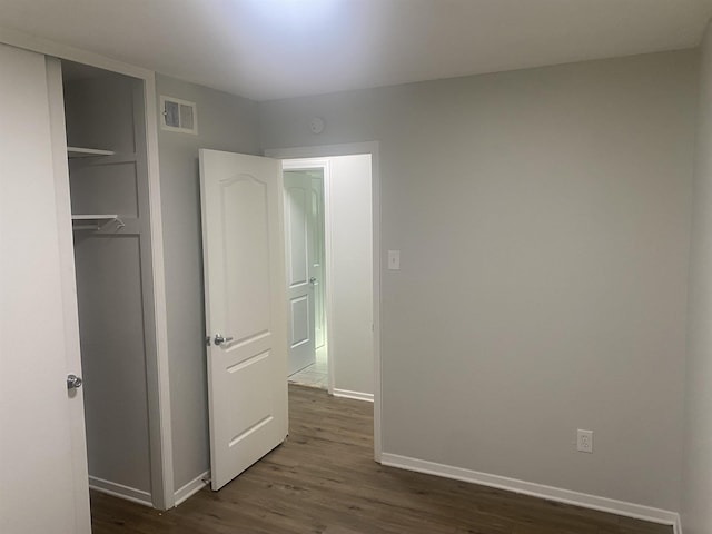 interior space featuring dark wood-type flooring, a closet, visible vents, and baseboards