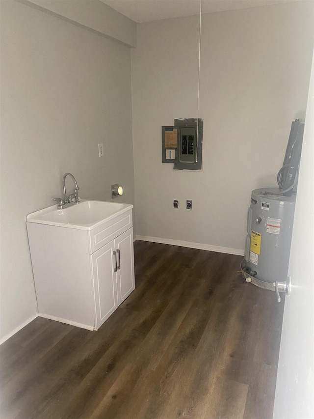 washroom with dark wood finished floors, water heater, a sink, electric panel, and baseboards