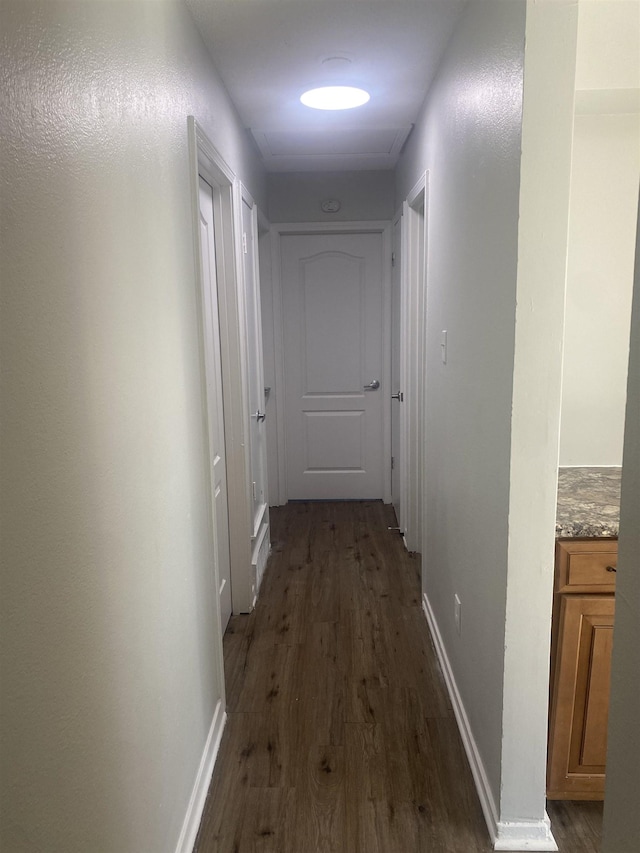 hallway featuring dark wood-style floors and baseboards
