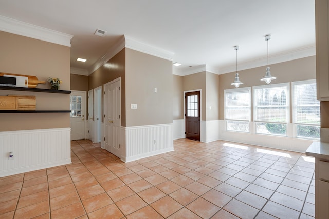 empty room with light tile patterned floors, visible vents, ornamental molding, and wainscoting