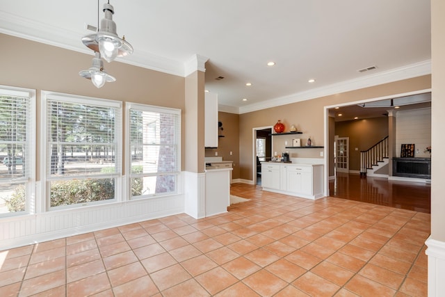 kitchen with light tile patterned floors, visible vents, white cabinets, light countertops, and ornamental molding