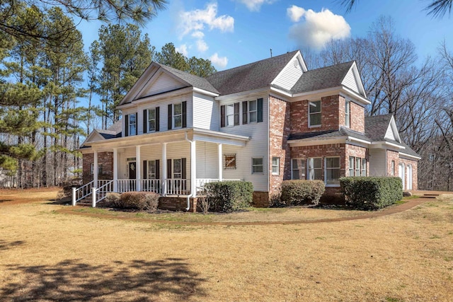 view of front of property with a garage, a front yard, covered porch, and brick siding