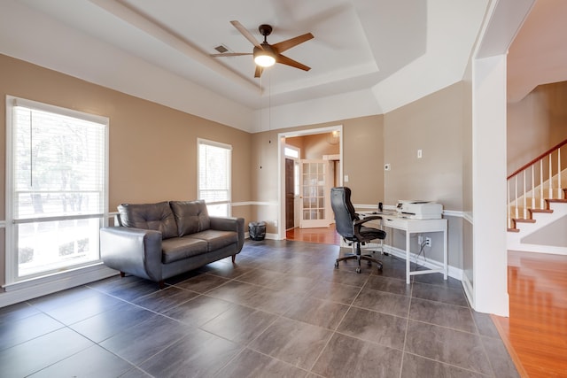 office area with a ceiling fan, dark tile patterned floors, a tray ceiling, and baseboards