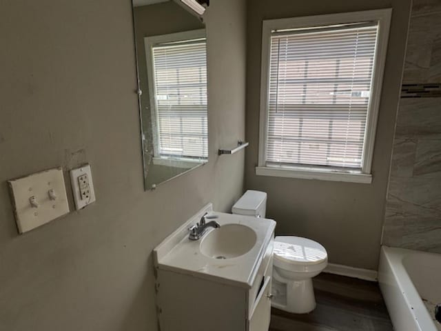 bathroom with a washtub, a wealth of natural light, vanity, and toilet