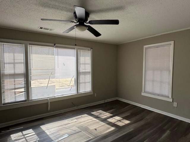 empty room featuring visible vents, dark wood-type flooring, ceiling fan, a textured ceiling, and baseboards