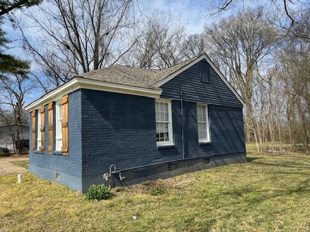 view of side of home with crawl space, a yard, and brick siding