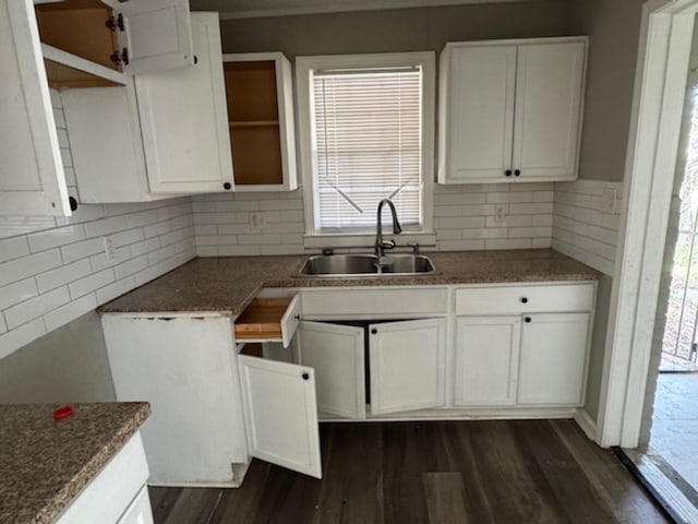 kitchen featuring dark wood-style flooring, white cabinetry, a sink, and backsplash