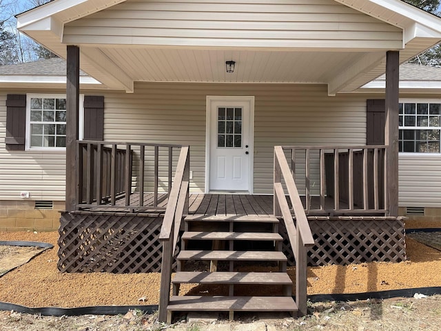 entrance to property with crawl space, a deck, and roof with shingles