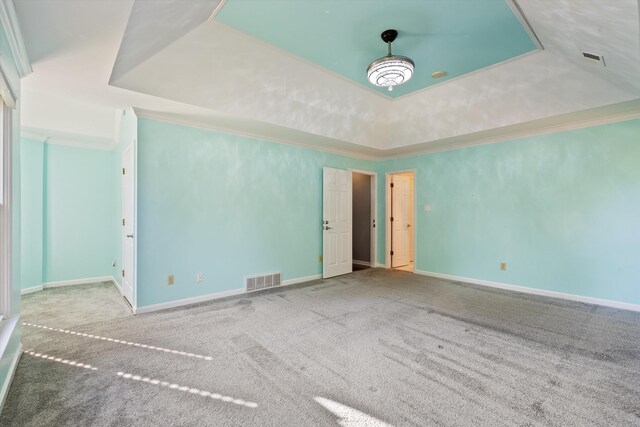 unfurnished room featuring carpet floors, visible vents, a tray ceiling, and baseboards