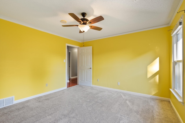 carpeted empty room featuring crown molding, visible vents, a ceiling fan, a textured ceiling, and baseboards