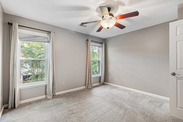 carpeted empty room with a textured ceiling, a ceiling fan, and baseboards