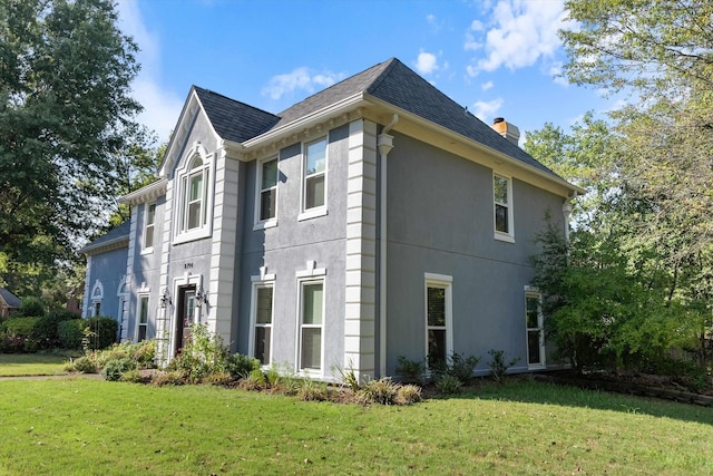 view of property exterior with roof with shingles, a lawn, a chimney, and stucco siding