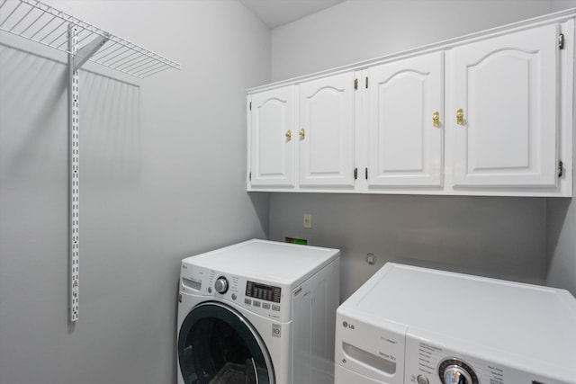 clothes washing area featuring cabinet space and separate washer and dryer