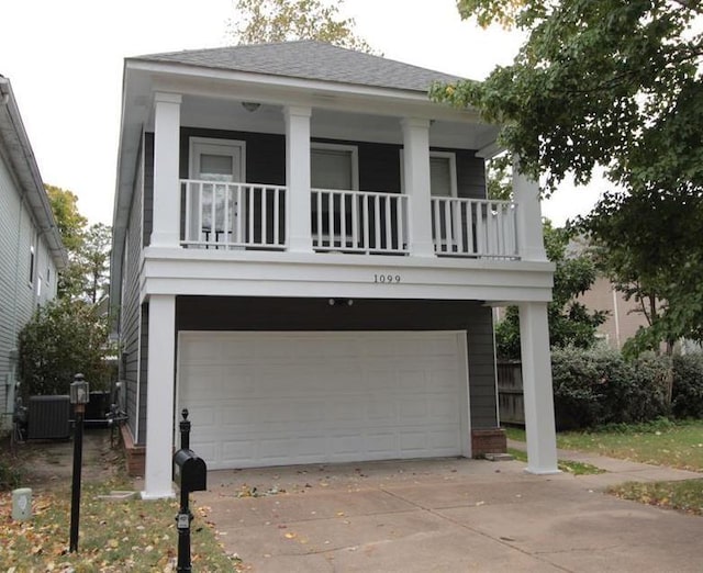 view of front of house with a garage, driveway, a shingled roof, and cooling unit