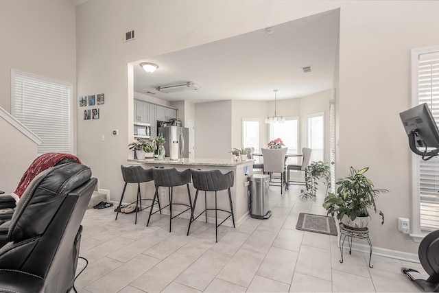 kitchen featuring decorative light fixtures, a breakfast bar area, visible vents, appliances with stainless steel finishes, and a peninsula