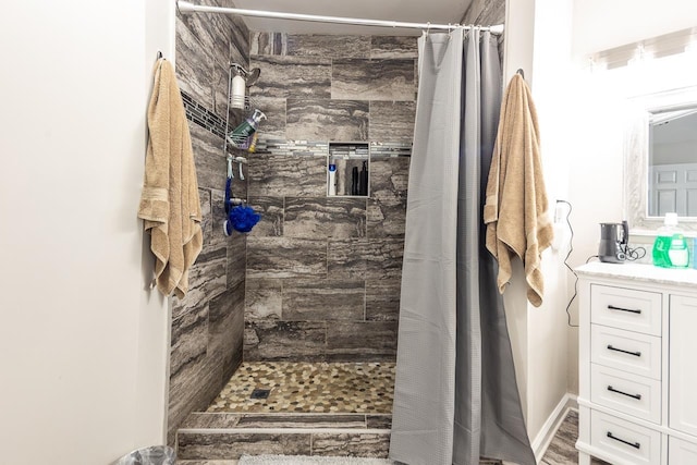 bathroom with a tile shower and vanity