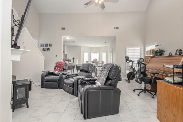 living area with a wood stove, light tile patterned floors, ceiling fan, and visible vents