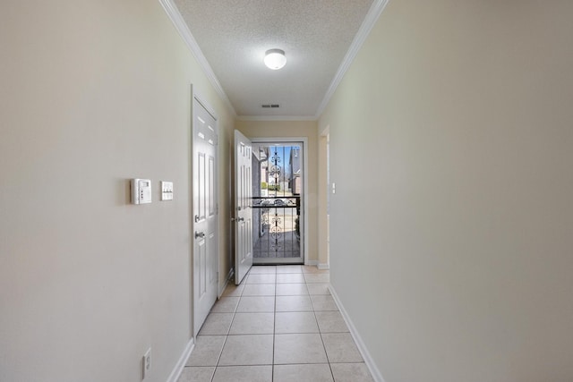 entryway with ornamental molding, a textured ceiling, baseboards, and light tile patterned floors