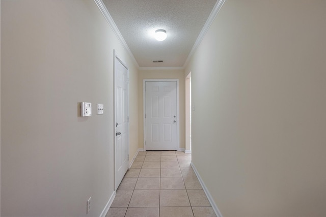 corridor with crown molding, visible vents, light tile patterned flooring, a textured ceiling, and baseboards