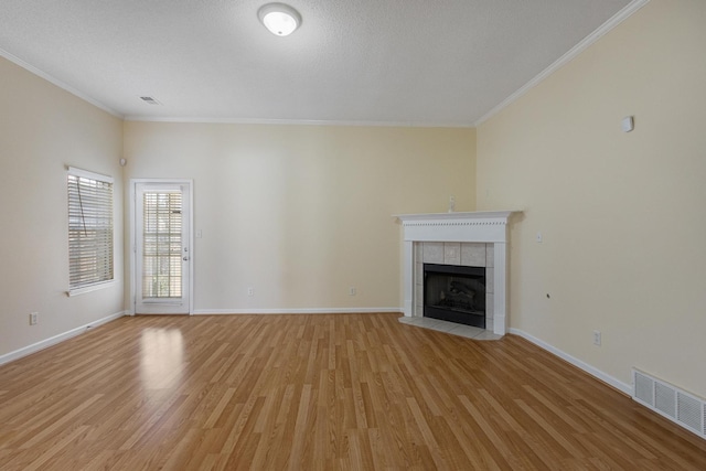 unfurnished living room with baseboards, visible vents, crown molding, light wood-style floors, and a fireplace