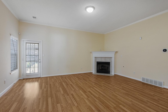 unfurnished living room featuring light wood finished floors, baseboards, visible vents, and a tile fireplace