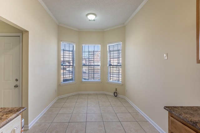 interior space featuring ornamental molding, light tile patterned flooring, a textured ceiling, and baseboards