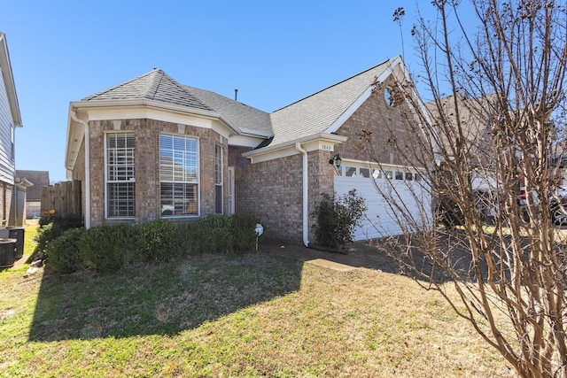 view of front facade with central air condition unit, a garage, brick siding, a shingled roof, and a front yard