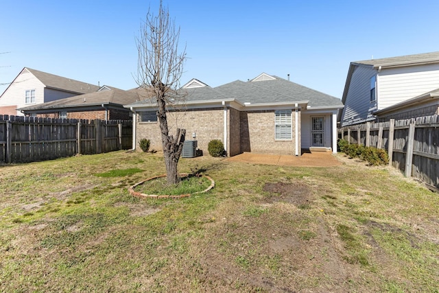 rear view of property featuring brick siding, roof with shingles, a lawn, cooling unit, and a fenced backyard