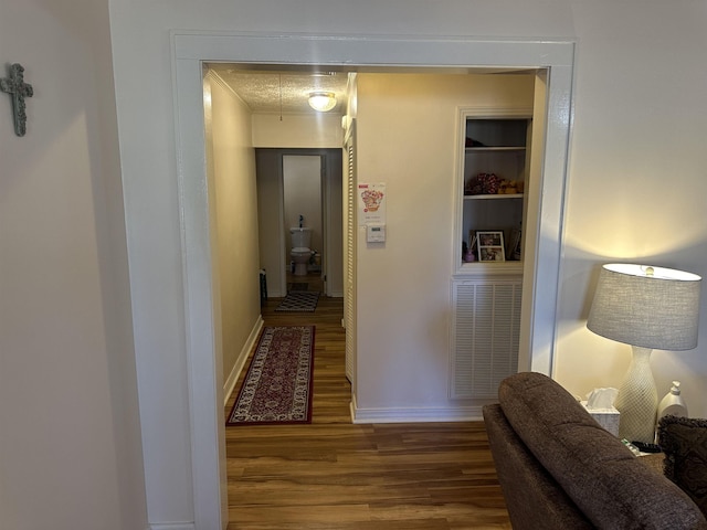 hall featuring attic access, ornamental molding, baseboards, and wood finished floors