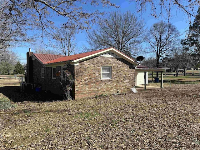 view of home's exterior featuring a chimney, metal roof, and brick siding