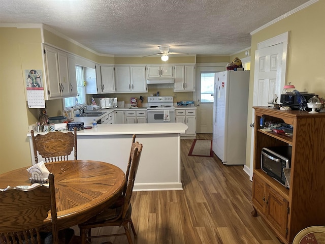 kitchen featuring a sink, a peninsula, wood finished floors, white appliances, and under cabinet range hood