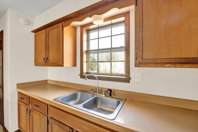 kitchen featuring brown cabinetry, a sink, and light countertops