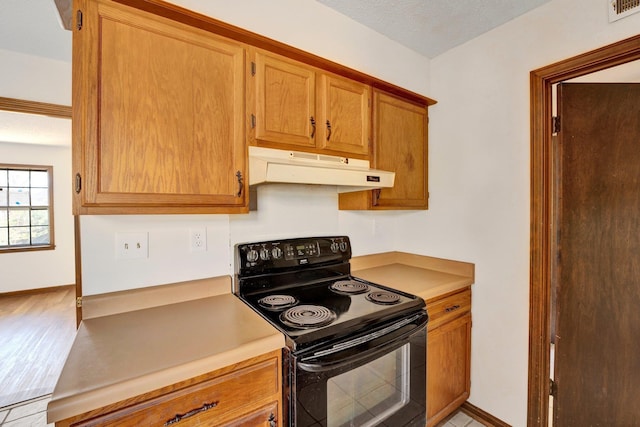 kitchen with under cabinet range hood, electric range, visible vents, and baseboards