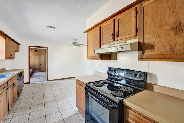 kitchen with brown cabinets, light countertops, visible vents, under cabinet range hood, and black appliances