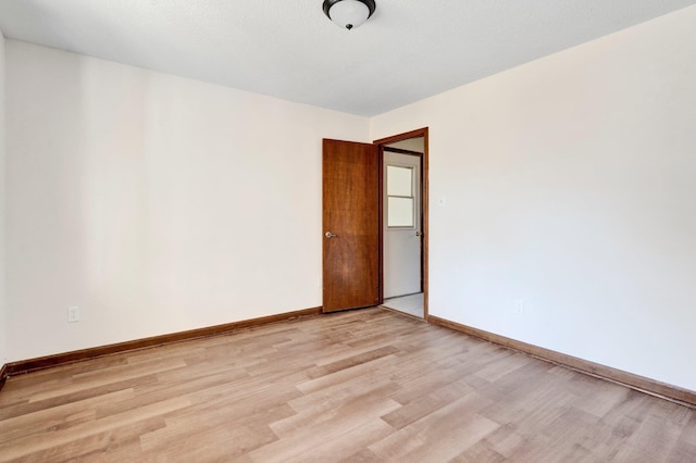 unfurnished room with light wood finished floors and baseboards