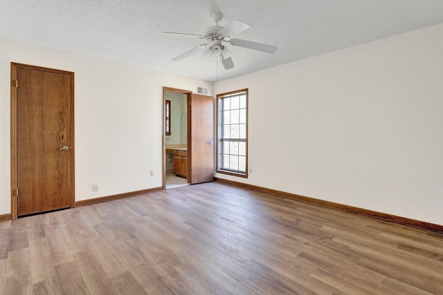 unfurnished bedroom with visible vents, a textured ceiling, baseboards, and wood finished floors