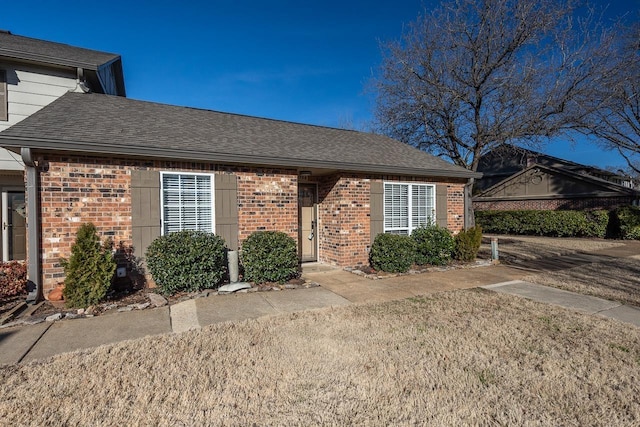 single story home featuring a shingled roof and brick siding